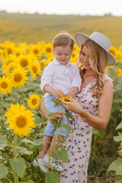 Happy young family, mother father and son, are smiling, holding and hugging in the sunflower field