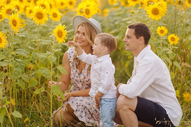 Free Photo happy young family, mother father and son, are smiling, holding and hugging in the sunflower field