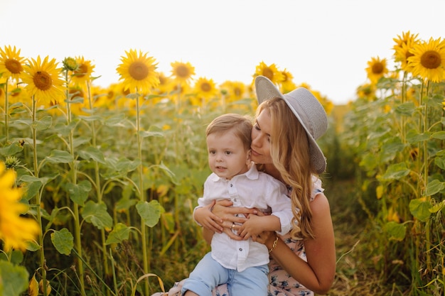 Happy young family, mother father and son, are smiling, holding and hugging in the sunflower field