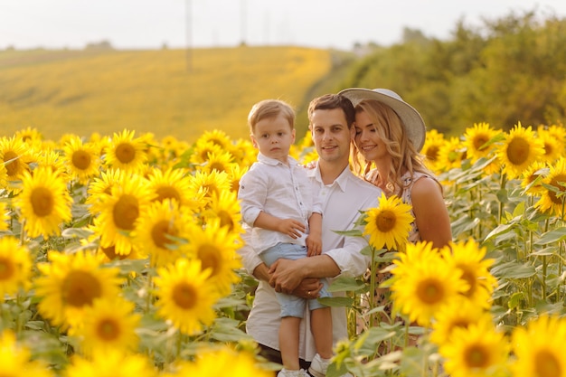 Free Photo happy young family, mother father and son, are smiling, holding and hugging in the sunflower field