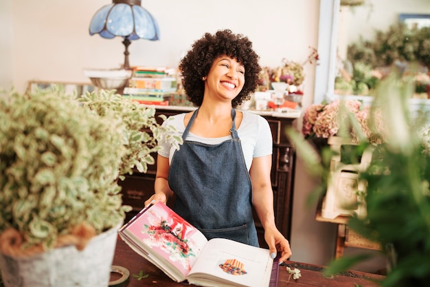 Happy young female florist with flower photo album in shop