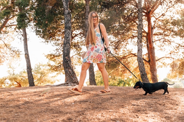 Happy young female strolling with her pet in park