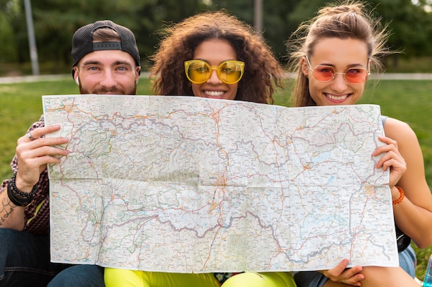 Free photo happy young funny company of friends tourists hiding behind map in sunglasses, man and women having fun together, traveling