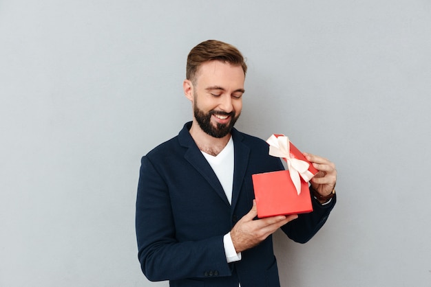 Free photo happy young handsome man looking at red gift isolated