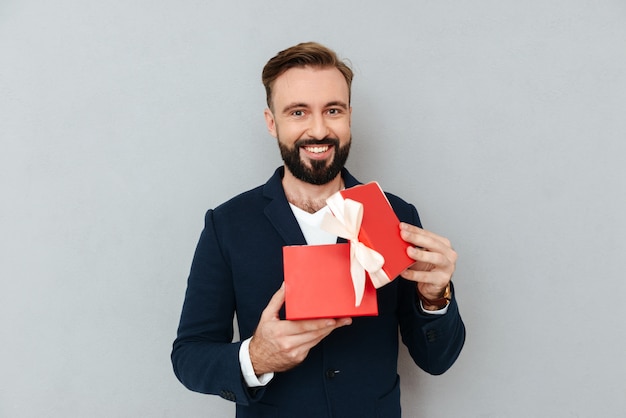 Free photo happy young handsome man looking at red gift isolated