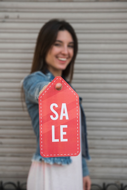 Happy young lady with sale tablet near profiled sheeting wall