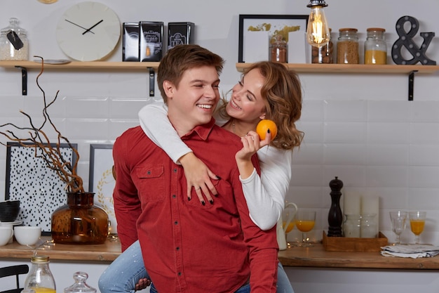 Happy young lovely couple on kitchen hugging each other. They enjoy spending time togehter. The man holding his girlfriend