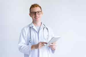 Free photo happy young male doctor using tablet computer