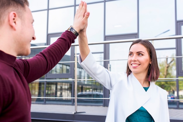 Free photo happy young male and female friend giving high five at outside