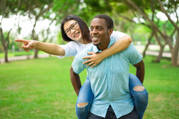 Happy young man giving piggyback ride to girlfriend or friend.