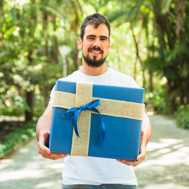 Happy young man holding blue gift box