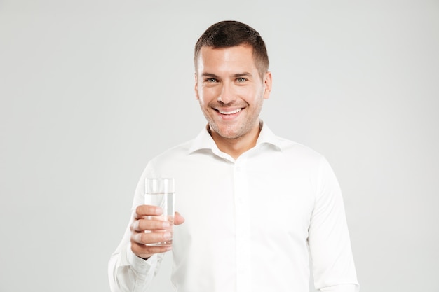 Happy young man holding glass full of water.