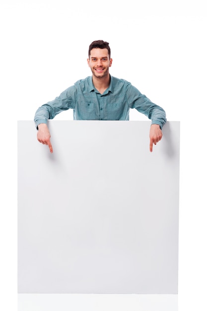 Free photo happy young man pointing at empty board