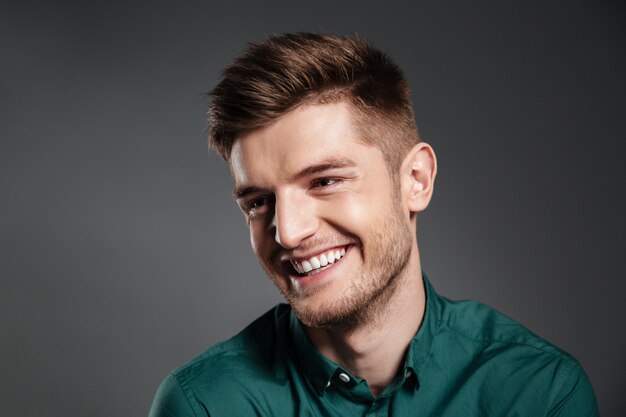 Happy young man posing isolated over grey