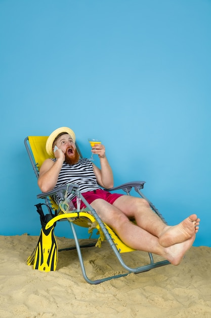 Free photo happy young man resting, takes selfie, drinking cocktails on blue  space