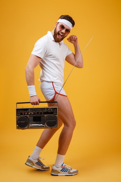 Free photo happy young man wearing sunglasses holding tape recorder