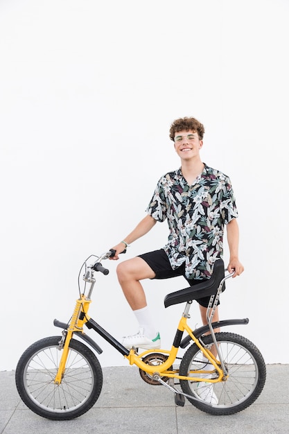 Free photo happy young man with bicycle standing on sidewalk