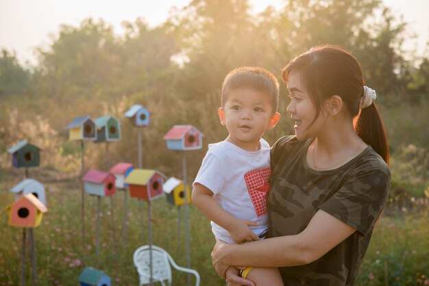 Happy young mother playing and having fun with her little baby son in the park on a sunny summer day