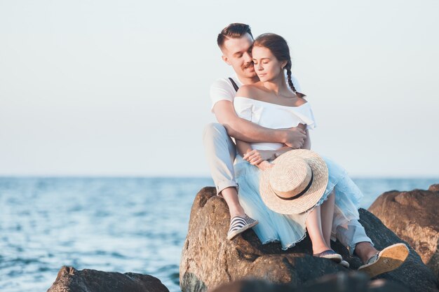 Happy young romantic couple relaxing on the beach and watching the sunset