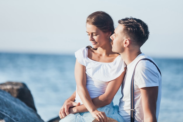 Happy young romantic couple relaxing on the beach and watching the sunset