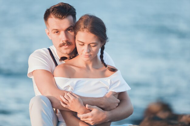 Happy young romantic couple relaxing on the beach and watching the sunset