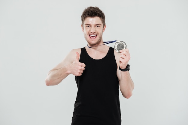 Happy young sportsman holding medal