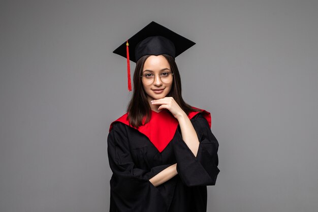 Happy young student with diploma on grey