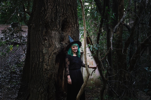 Free photo happy young witch near tree