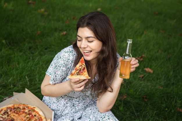 Free photo happy young woman eating pizza at a picnic