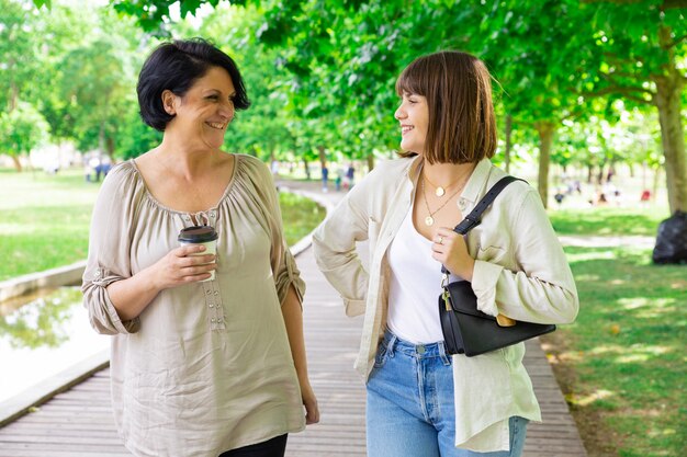 Happy young woman and her mother chatting and walking in park