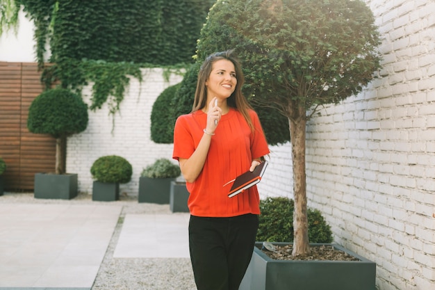 Happy young woman holding diary in backyard