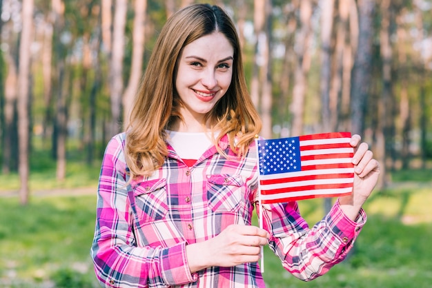 Happy young woman holding flag of USA