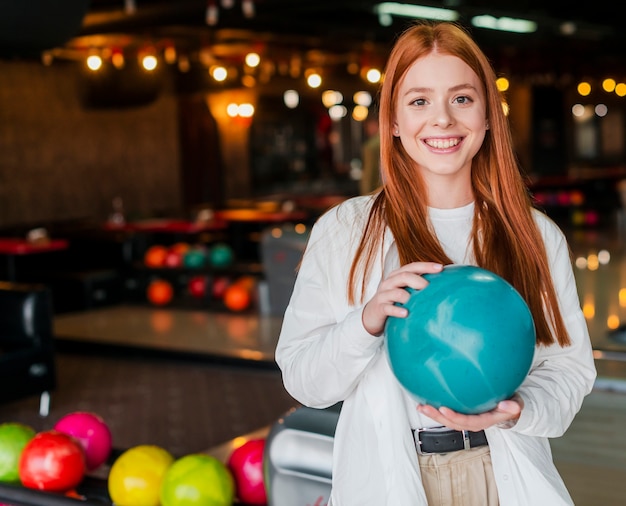 Happy young woman holding a turquoise bowling ball