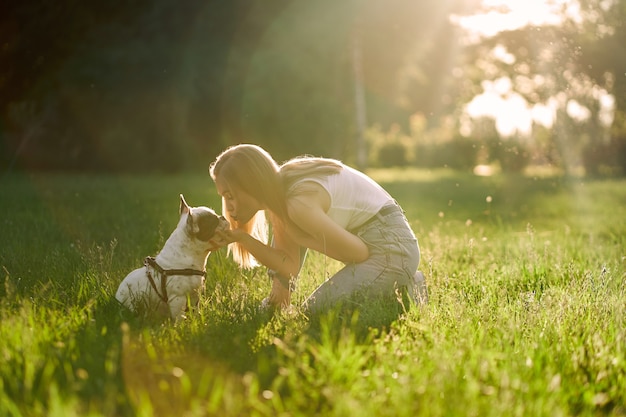 Happy young woman kissing french bulldog in park