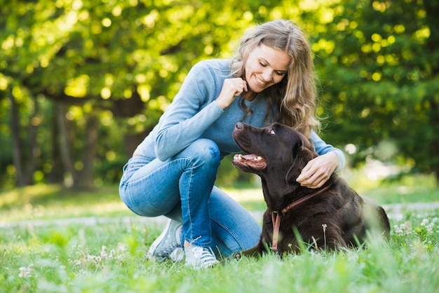 Happy young woman looking at her dog in park