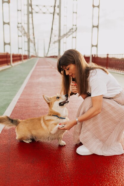 Happy young woman playing with corgi