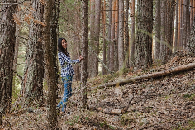 Free photo happy young woman posing next to a tree