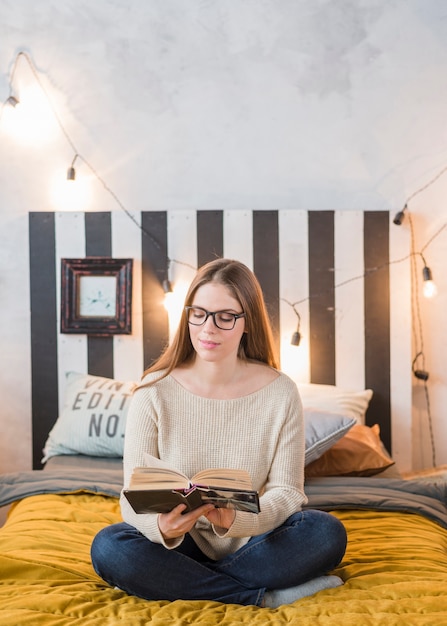 Free photo happy young woman reading book in the bedroom