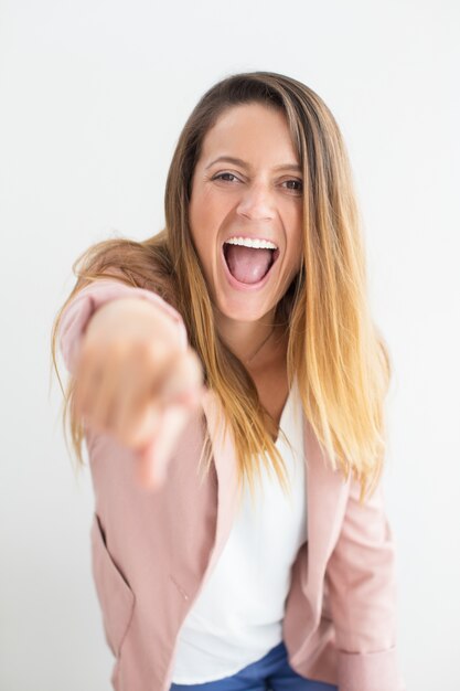 Happy young woman shouting and pointing at camera