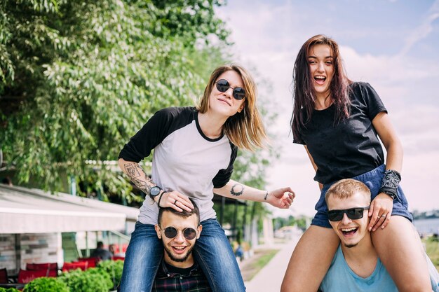 Happy young woman sitting on boyfriend's shoulder at park