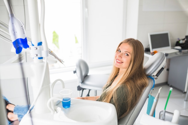 Free photo happy young woman sitting on dental chair