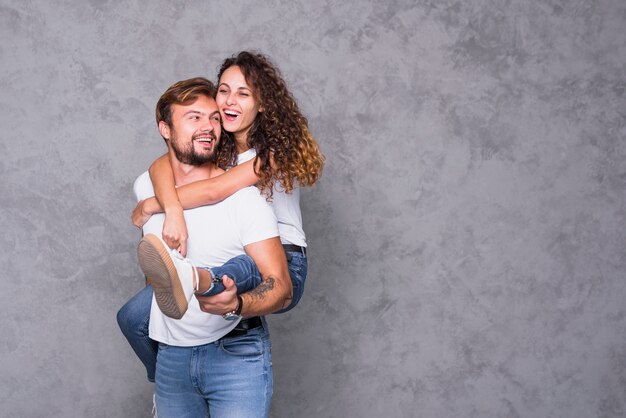 Happy young woman sitting on man back