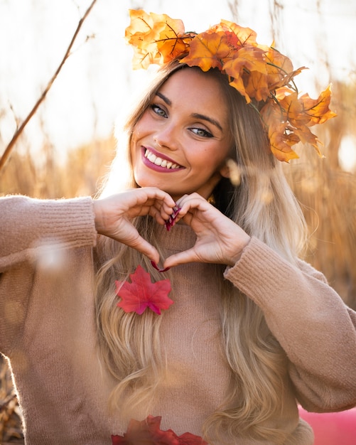 Free photo happy young woman smiling and making heart shape with hand at outdoors