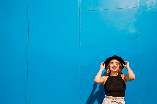 Happy young woman standing against blue wall