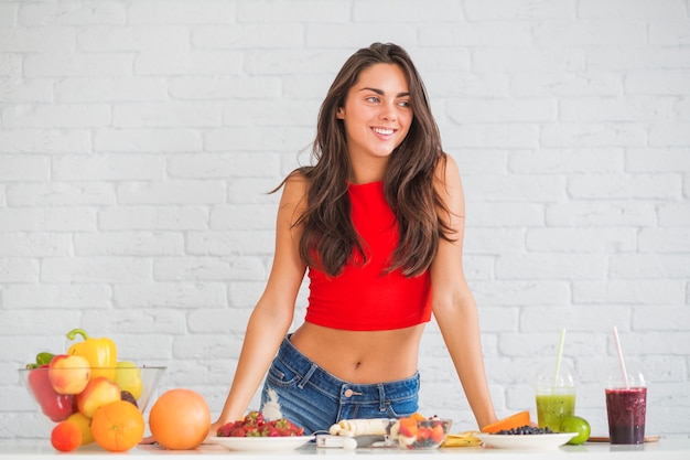 Happy young woman standing behind table with healthy food