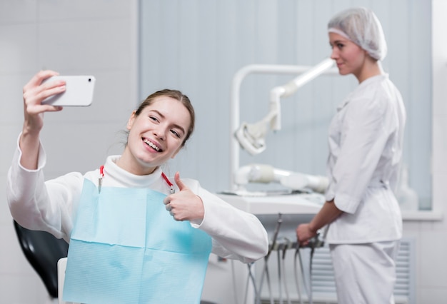 Free photo happy young woman taking a selfie at the dentist