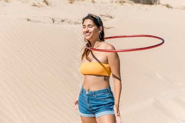 Happy young woman turning hula hoop around neck