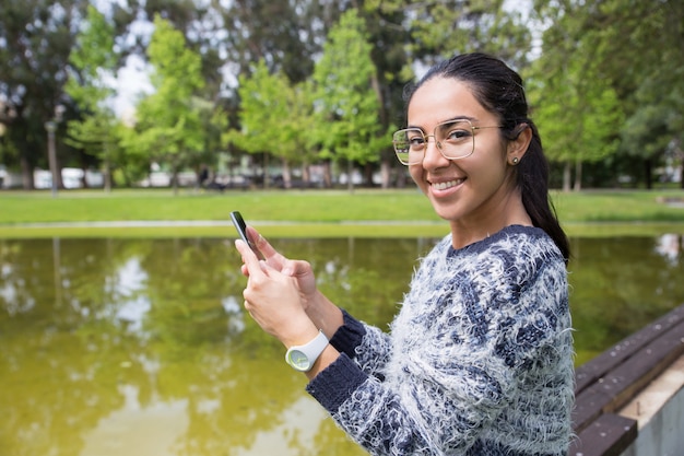 Happy young woman using smartphone in park