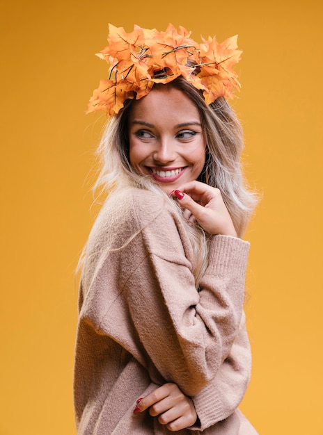 Free photo happy young woman wearing tiara and posing against yellow wall