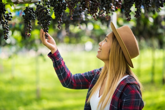 Free Photo happy young women gardener holding branches of ripe blue grape